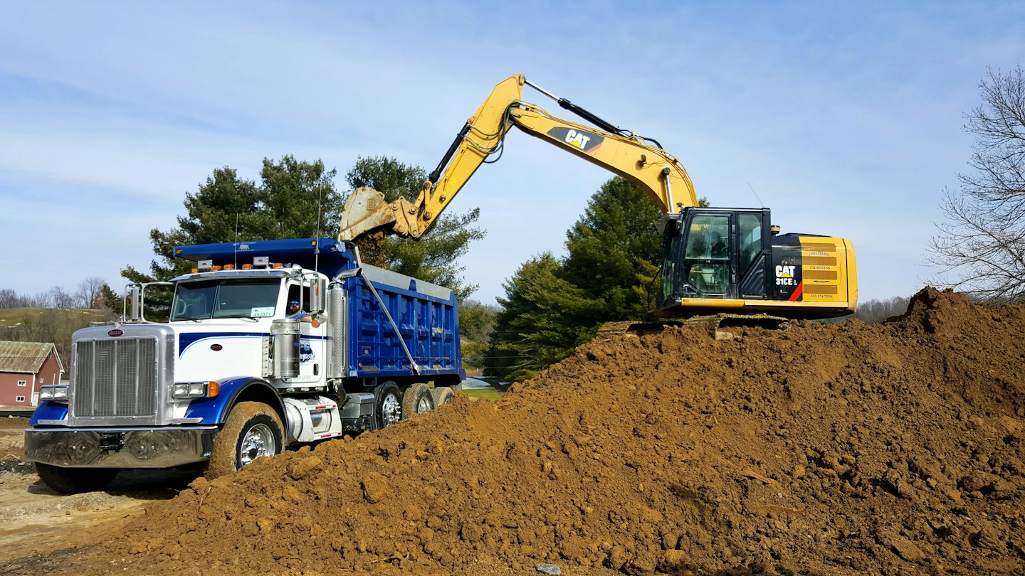 Ein Bagger lädt Erde auf einer Baustelle in einen LKW.